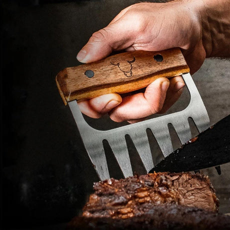 Mano sosteniendo un tenedor para carne con mango de madera y logo de toro grabado, mientras corta una pieza de carne asada.