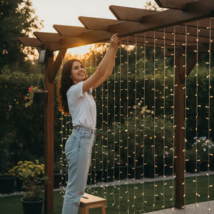Mujer instalando cortina luces LED solar jardín exterior luz cálida decorativa
