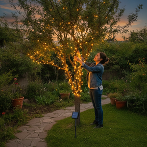 Mujer decorando árbol jardín con guirnalda solar luz cálida exterior