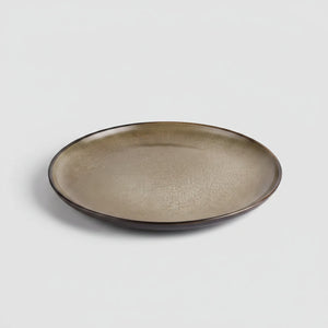 Mujer poniendo plato stoneware bronce en mesa familiar chilena