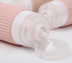Mano exprimiendo botella silicona rosa dispensando crema botellas viaje rellenables