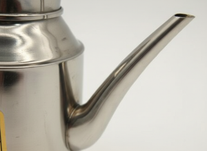 Jarra acero inoxidable vertiendo té taza cerámica cocina moderna