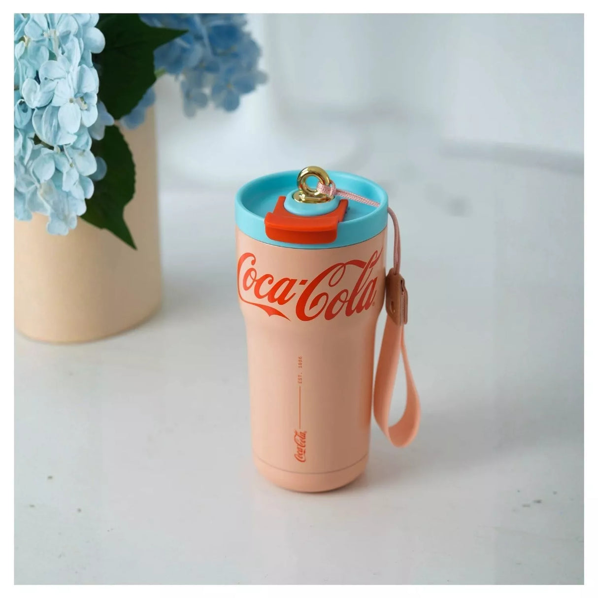 Mujer chilena sosteniendo tumbler Coca Cola rosa GERM con cordón cuero