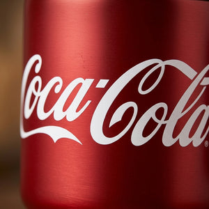 Mujer sosteniendo tumbler Coca-Cola GERM rojo en parque soleado
